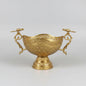 An ornate gold-toned metal serving bowl with intricate embossed floral patterns and decorative handles, displayed on a dark marble table in what appears to be a shop or showroom.