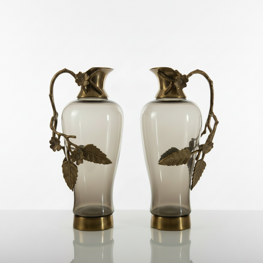 Two ornate vases with gold accents on a white platform, accompanied by a brown leather notebook and gold pens, with 'The Handicraft People' logo in the corner.