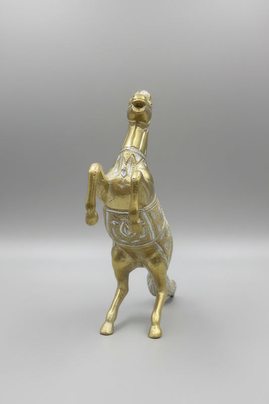 Gold horse figurine on a reflective surface with a blurred background