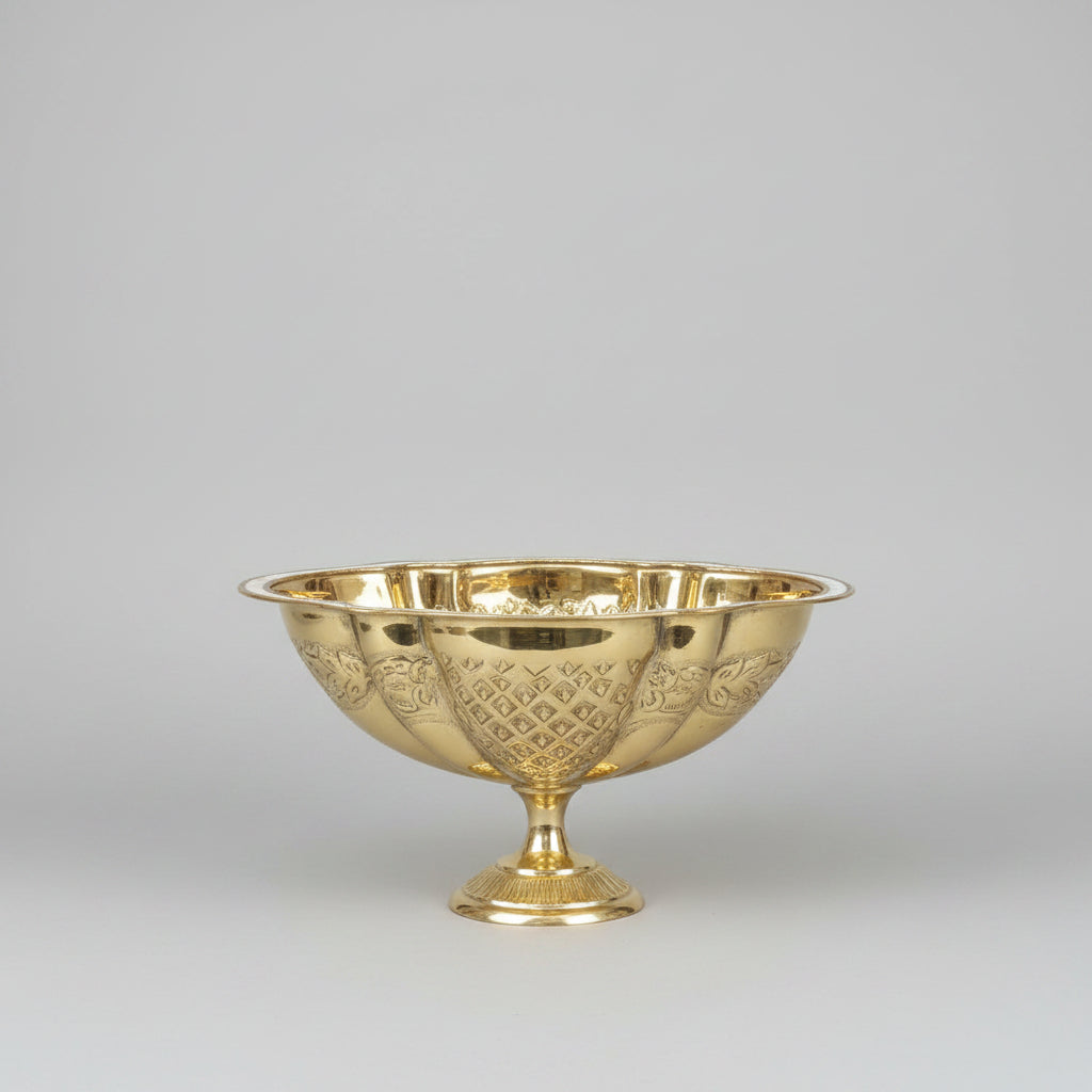 A shiny gold pedestal bowl with a cut crystal pattern, displayed on a reflective marble counter inside what appears to be a shop or showroom.