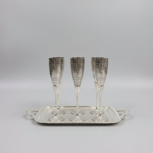 Set of silver champagne flutes on a metal tray with a blurred background